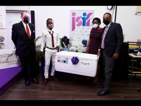 Credit: Nicholas Nunes/Photographer Fisherman Shawn Castell (second left) is presented with an igloo and fishing equipment by Jamaica Social Investment Fund Managing Director Omar Sweeney (right) yesterday as Industry, Commerce and Investment Minister Audley Shaw (left) and St Andrew South W