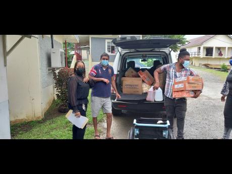 Credit: Photo by Gareth Davis Businesswoman Dion Lindo knocks elbows with a member of the Hooda family from the United States during the handing out of food and other basic items to the Portland Infirmary.