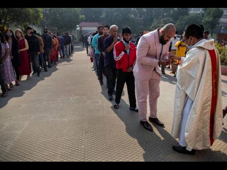 Credit: AP Indian Christians, many wearing face masks as a precaution against the coronavirus, line up to receive holy communion from the priest at a church on Christmas in Gauhati, India on Christmas Day.