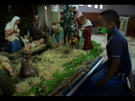 Credit: AP A child kneels at a nativity scene prior to a morning Christmas Mass at the Rosebank Catholic Church in Johannesburg on Friday.