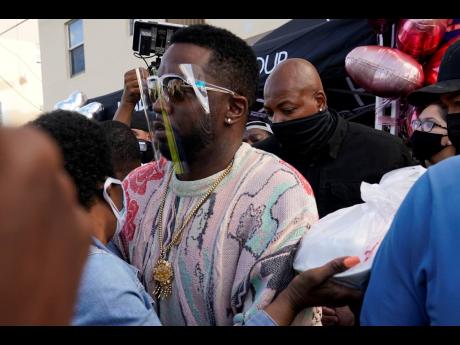 Rapper Sean ‘Diddy’ Combs passes out US$50 bills to residents in the Overtown neighbourhood of Miami on Tuesday. 