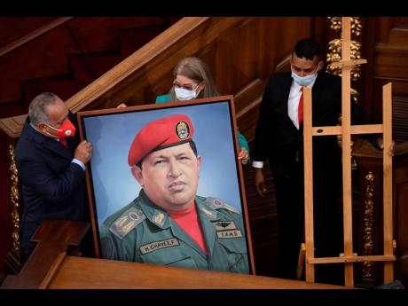 Credit: AP First Lady Cilia Flores (centre) and Socialist party leader Diosdado Cabello (left) carry a portrait of late Venezuelan President Hugo Chávez into the chamber of the National Assembly as the ruling socialist party prepares to assume the leadership of Cong