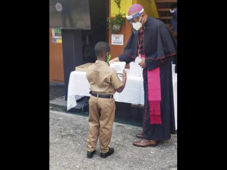 
Archbishop Kenneth Richards, Archdiocese of Kingston, presents a tablet to a student of Holy Family Primary and Infant School. This initiative was in partnership between Boston College and Royale Computers and Accessories.