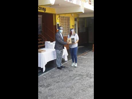 Jordian Nakash (right), class of 2024 student at Boston College, presents a tablet to principal of Holy Trinity High School, the Rev Carl F. Clarke, on Thursday, January 7.
