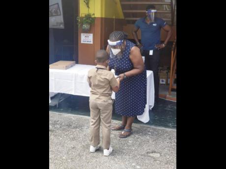 Margaret Brissett-Bolt, education consultant, Archdiocese of Kingston, presents a tablet to a student of Holy Family Primary and Infant School on Thursday, January 7.
