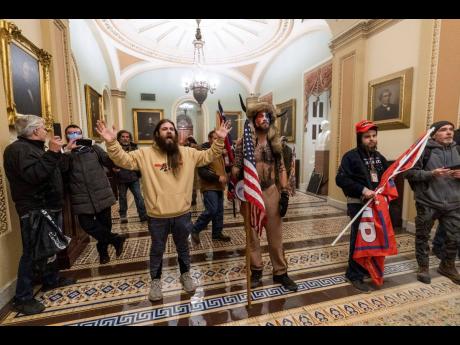 In this January 6, 2021 photo supporters of President Donald Trump are confronted by US Capitol Police officers outside the Senate Chamber inside the Capitol in Washington. Jacob Anthony Chansley, the Arizona man with the painted face and wearing a horned,