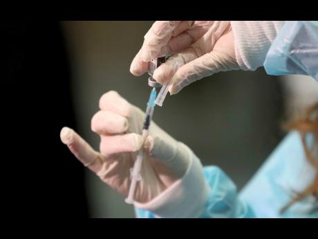 A medical worker holding a Pfizer-BioNTech vaccine and a syringe during mass vaccination starts in Vienna, Austria, Friday, January 15, 2021. Authorities started to vaccinate the most vulnerable people in a coordinated effort.