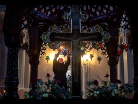 A Lithuanian Orthodox Church believer lights candles before the liturgy on Orthodox Christmas Eve in the Prechistensky, the Cathedral Palace in Vilnius, Lithuania, Tuesday, January 5, 2021. The Orthodox church cancelled all worship services but is open onl