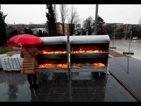A woman lights candles during the Orthodox Christmas Eve, in front of St Sava temple, in Belgrade, Serbia, Wednesday, Jan.uary 6, 2021. Orthodox believers in Serbia celebrate Christmas on January 7, according to the Julian calendar.