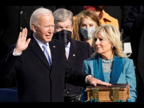 Joe Biden is sworn in as the 46th president of the United States by Chief Justice John Roberts as Jill Biden holds the Bible during the 59th Presidential Inauguration at the US Capitol in Washington yesterday. 
