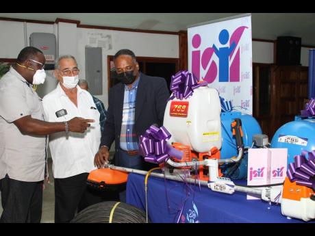 Dwight Lawrence (left) of Treadlight Farms in Clarendon expresses appreciation to William Shagoury (centre) and Omar Sweeney, managing director of JSIF, for the items he received that will aid in increasing production on his farm.