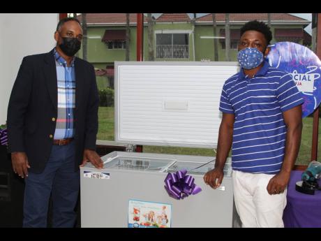 Poultry farmer Nicolus Grant (right) of Treadlight, Clarendon, accepts a freezer from Omar Sweeney, managing director of the Jamaica Social Investment Fund, last Friday.