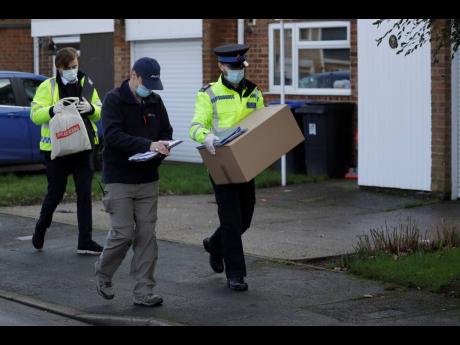 A police volunteer carries a box of home testing kits for COVID-19 from Britain’s Department of Health as they go house-to-house distributing them to residents, in Woking, England, yesterday.