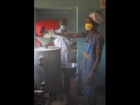 Credit: Nathaniel Stewart/Photographer Domonic Burrell operates the grinder, one of the machines Lincoln Gordon (looking on) built in his workshop for his agro-processing business.