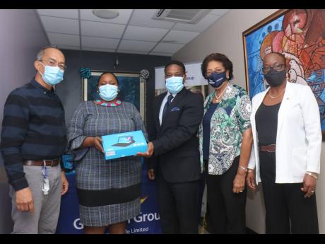 Principal of Flanker Primary, Collette Barns (second left), receives a donation of tablet computers from Oniel Brooks (centre), regional branch manager of Guardian Life. Looking on is National Security Minister Dr Horace Chang (left).