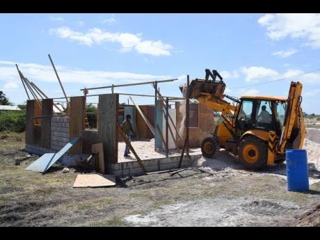 Credit: Kenyon Hemans/Photographer Two contractors working on a Food For The Poor home for Shian Ganpatt in McCook’s Pen, St Catherine, yesterday. Ganpatt and her two children were among 15 families displaced after their Inswood Estates dwellings were demolished by SCJ Holdings Limited la