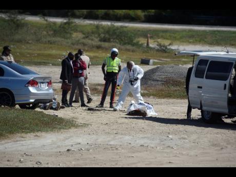 Police investigators process a scene in Portmore, St Catherine, where the bodies of Nicholas Neufville and Raheima Edwards were discovered with multiple gunshot wounds yesterday.