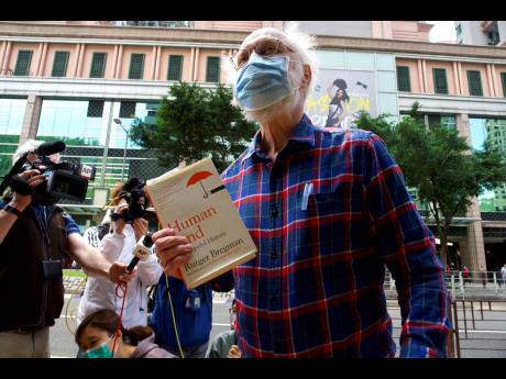 John Clancey, an American lawyer who became the first foreigner arrested under Hong Kong’s national security law, displays a book before appearing at a police station in Hong Kong.