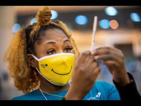 Medical Assistant Keona Shepard holds up the Johnson & Johnson COVID-19 vaccine as she prepares to administer it at the New Orleans Ernest N. Morial Convention Center during the mass coronavirus vaccination in New Orleans, in this Thursday, March 4, 2021 p