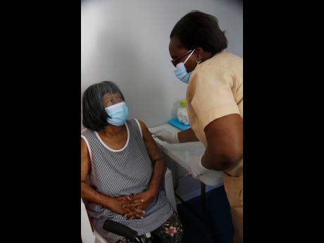 Credit: Nathaniel Stewart/Photographer Public health nurse Ann-Marie Menzie administers the COVID-19 vaccine to Herman Bryant-Manning, an 81-year-old retired nurse, at the May Pen Hospital vaccination centre in Clarendon yesterday. Bryant-Manning, a nurse for 50 years, says she has never seen a