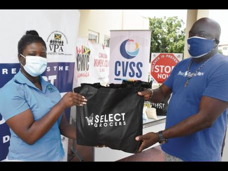 Credit: Contributed Jonelle Llewellyn (left), research associate at the Violence Prevention Alliance, presents Milton Tomlinson, Peace Management Initiative’s intervention manager, with care packages for distribution to East Kingston communities in observation of Internatio