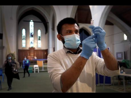Pharmacist Rajan Shah prepares a syringe of the AstraZeneca vaccine at St John’s Church, in Ealing, London, yesterday. 