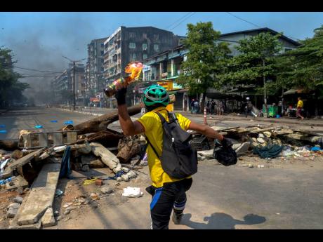 An anti-coup protester throws a molotov cocktail towards police as they move towards the protest area in Yangon, Myanmar, yesterday.