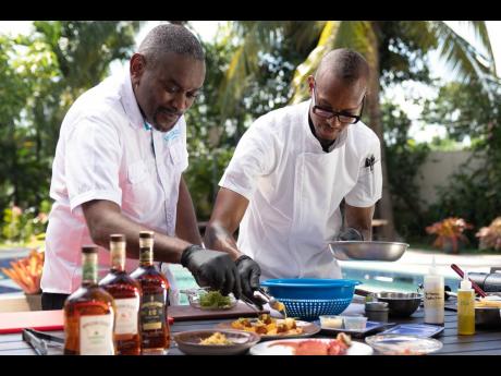 Senior Blender at Appleton Estate, David Morrison (left), gets in on the culinary action, placing dollops of cream cheese over the scrumptious King Crab Nachos alongside Executive Chef Brian Lumley.