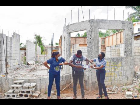 Marie Brown (left), branch account associate, National Commercial Bank (NCB), Rayon Ellis and Jean Davy, service quality manager, NCB, at the site where Ellis had begun rebuilding his family home.