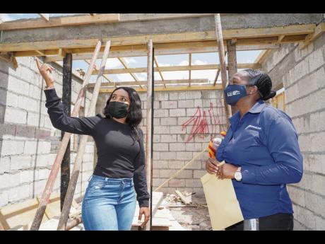 Ayana Humber (left), shows Zonya Pryce, project officer, NCB Foundation, around the site where her house is now being rebuilt following the fire in late 2020. 