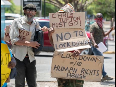 Anti-government crusader Lloyd D’Aguilar and anti-vaccination protesters demonstrate in the vicinity of the Ministry of Health and Wellness’ headquarters in New Kingston on Wednesday.