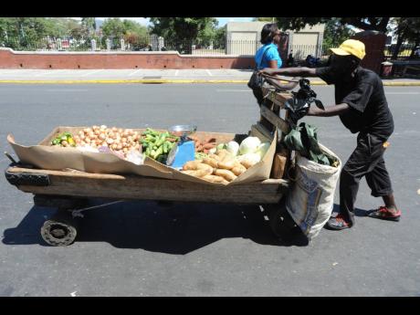 
In this 2014 file photo, a vendor pushes his handcart laden with produce in downtown Kingston. 