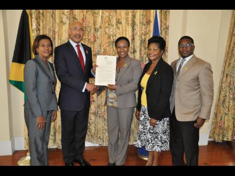 The BASE team (from left): Sonia Fuller, Shauna Fuller Clarke and Ricardo Clarke receive a declaration from Governor General Sir Patrick Allen. 