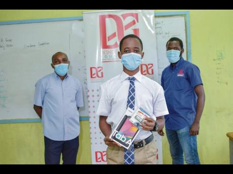 Student at the St Thomas-based Yallahs High School, Lawayne Lamont, displays one of several tablets donated to male students at the school by the Desnoes & Geddes Foundation, under the organisation’s ‘No Male Left Behind’ project. In the background a