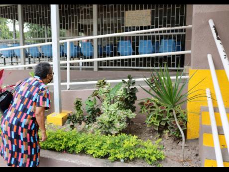 A senior citizen tries to read the hand written sign at the Edna Manley Health Centre in Grants Pen, St. Andrew advising of the shifting of the vaccination centre to the National Arena. She was one of the many persons who received an email confirming the t