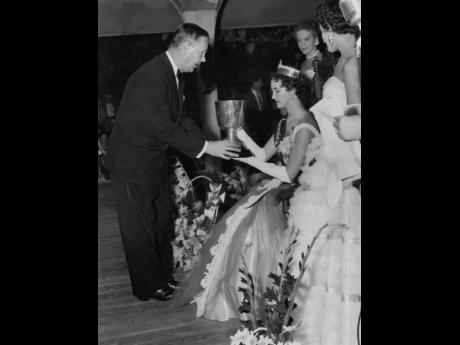 John Basford, then manager of Barclays Bank, Kingston (left), presenting the Goya Cup to Miss Jamaica 1955 Marlene Milnes-Fenton at the Glass Bucket Club on December 3. Runners up Jennifer Campbell and Dorothy DeLisser look on. 
