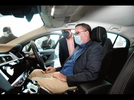 British High Commissioner to Jamaica, Asif Ahmad CMG explains a few standout features of the Jaguar I-Pace to Energy Minister Daryl Vaz (seated) at its official launch on Thursday, April 8 at Stewart’s Automotive Jaguar Land Rover showroom in Kingston.