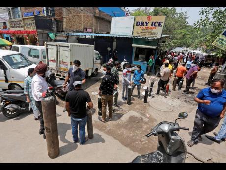 People stand in a queue to refill oxygen in cylinders in New Delhi, India yesterday. India put oxygen tankers on special express trains as major hospitals in New Delhi on Friday begged on social media for more supplies to save COVID-19 patients who are str