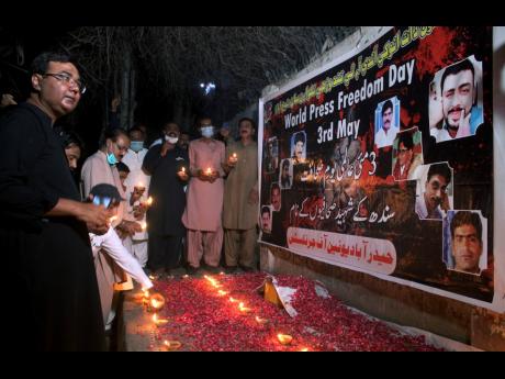 Members of the media place clay lamps in front of a banner with the pictures of killed journalists during a vigil to pay tribute to  them on the eve of World Press Freedom Day in Hyderabad, Pakistan, on Monday. A committee of journalists in Pakistan said t