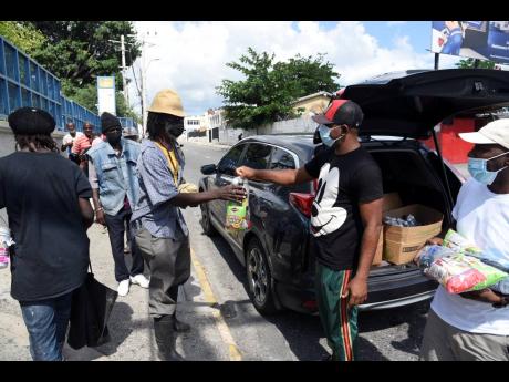 Members of Righteousness Promotions hand out care packages to the homeless in Half-Way Tree on Sunday.