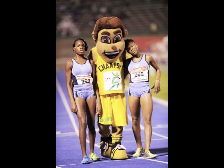 Marleena Eubanks (left) of Edwin Allen, winner of the Girls’ Class Two 1500m, and her teammate, Sanikee Gardner, are congratulated by Champs mascot Champsy, at the ISSA/GraceKennedy Boys and Girls’ Athletics Championships at the National Stadium on Fri