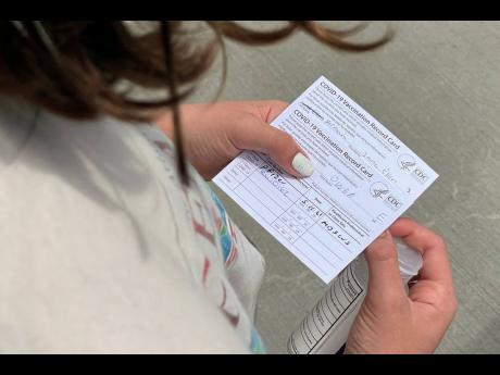 Credit: Angie Wang Jane Ellen Norman, 12, holds vaccination cards for her and her 14-year-old brother Owen outside Mercedes-Benz Stadium in Atlanta on Tuesday, May 11.