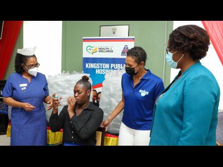 Kingston Public Hospital’s (KPH) secretary Omoy Blake (second from left) demonstrates the use of a modified medical spacer, created by the Wisynco Group Ltd, as a gesture to assist respiratory patients battling COVID-19. The spacers were designed and cre