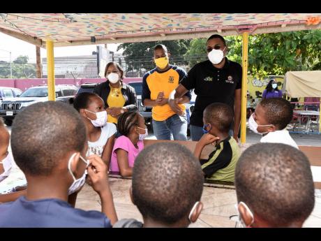Robert Morgan (third right), state minister in the Ministry of Education, talks with wards at the Nest Children’s Home just before the launch of a backyard garden project. It is the first of 52 backyard garden projects at children’s homes across the Is