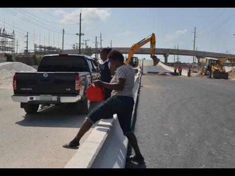 
In this file photo, Sophia Bogle and her child negotiate a median on Spanish Town Road, in the vicinity of Majesty Gardens. Experts say that building these high medians, Jersey barriers, is a mistake and contrary to best practices in the world.