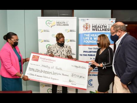 CIBC FirstCaribbean’s Human Resources Manager Jerome Griffith (left) and Alison Rattray, corporate secretary and legal counsel (second right), present the bank’s cheque for $19 million towards the purchase and roll-out of COVID-19 vaccines in Jamaica t