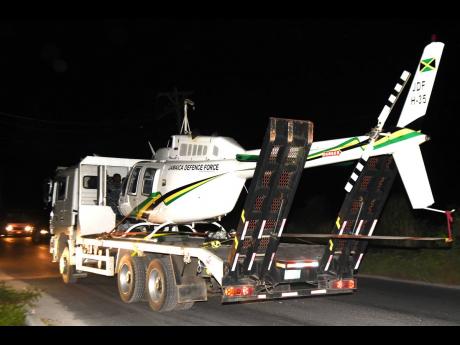 Credit: Kenyon Hemans/Photographer The Jamaica Defence Force helicopter being transported away from the site at which it landed in Dunbeholden, St Catherine, yesterday.
