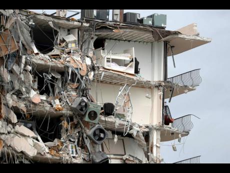 Items and debris dangle from a section of the oceanfront Champlain Towers South Condo that partially collapsed Thursday yesterday in the Surfside area of Miami, Florida.