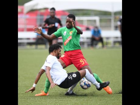 Cavalier player Vishnall Harrison slides in on Humble Lion's Linval Lewis in their Jamaica Premier  League match played at the UWI/JFF/Captain Horace Burrell Centre of Excellence on Saturday, June 26, 2021.