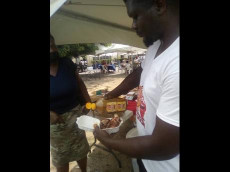 Howard Mathews pouring some of his Flava Fire Scotchy pepper sauce on a bit of chicken at the fair.